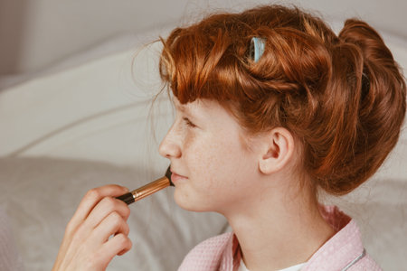 Happy family. Young beautiful mother does makeup of her beautiful daughter on the bed in the...