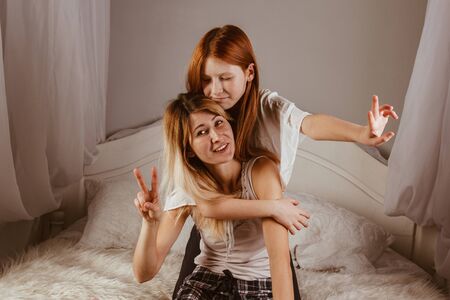 Happy mother's day. Mom and her daughter are playing girl, smiling and hugging in bed. Family holidays and togethernessの写真素材