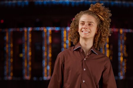 Celebration, people and holidays concept - happy curly guy having a Christmas or New Year party on the background of festive lightsの写真素材