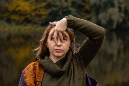 hide and seek. the girl covered her face with her hands. Close-up portrait on a lake background. The...