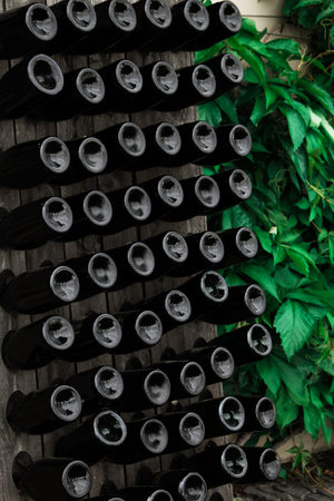 The bottom of the wine bottles is displayed on shelves in the open air. Creative dark and textured...