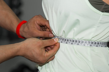 weight loss, personal trainer, nutritionist, fitness, motivation, healthy lifestyle. A man measures...