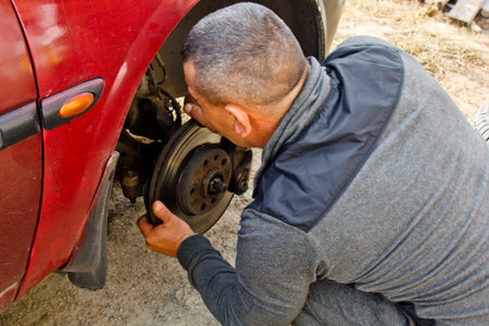 Service process. A man holds a tire in the garage. Replacing winter and summer tires. Seasonal tire replacement conceptの写真素材