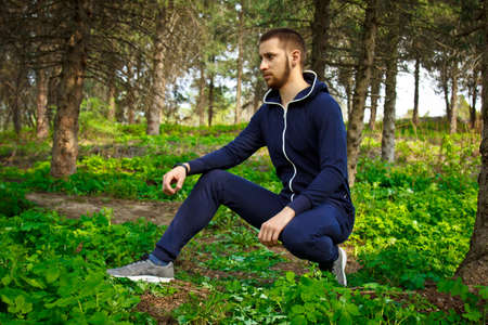 Handsome, young guy in a tracksuit plays sports in the park on the nature. Healthy lifestyleの写真素材