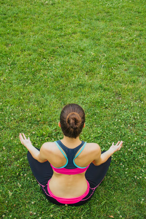 European girl in a light tracksuit doing yoga in the park in the afternoon in the summer. Gymnastics...