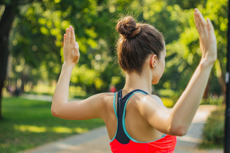 European girl in a light tracksuit doing yoga in the park in the afternoon in the summer. Gymnastics...