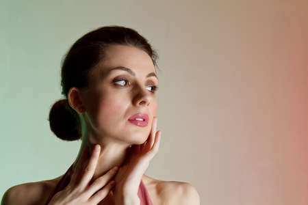 Colored background, neon lights, studio shot. Portrait of a young elegant brunette woman in a beautiful dress. Beauty salon conceptの写真素材