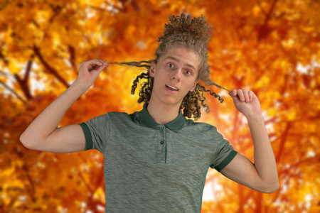 Autumn photo of a young guy in the park. Photo in warm colors. Against the background of yellow...