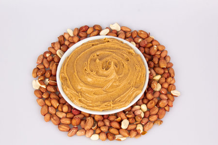 Creamy peanut butter, peanut butter in an open glass jar in the center of a peanut food background....