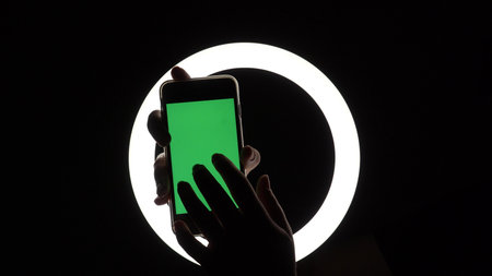 female hands show the phone close-up on a black background. green screen mockup for advertising...