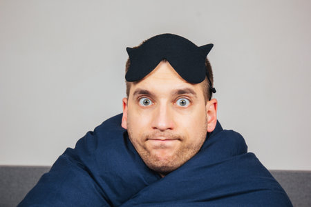 Photo of a young man, a happy positive smile closes his eyes with a mask before going to bedの写真素材