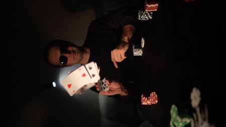 Bearded man plays poker in a casino. The person wins and effectively throws the cards on the table....