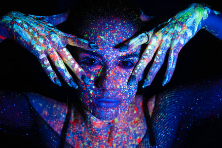 Fashion model woman in neon light, portrait of a beautiful model with fluorescent makeup, artistic design of disco dancers posing in UV, colorful makeup. isolated on black backgroundの写真素材