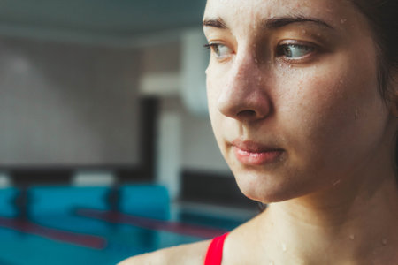 Young beautiful brunette girl on the background of the pool. Portrait of a girl near the side of the pool. Swimming, healthy lifestyleの写真素材