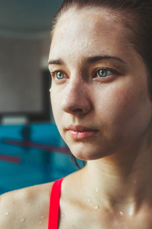 Young beautiful brunette girl on the background of the pool. Portrait of a girl near the side of the pool. Swimming, healthy lifestyleの写真素材