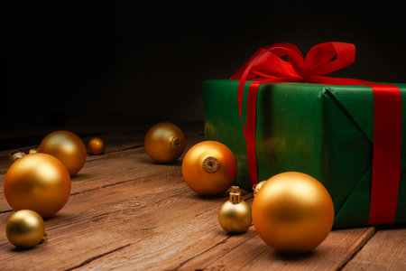 Festive gift box and golden Christmas tree decorations on wooden background. Holiday concept. Christmas, New Year, birthday, women's holidayの写真素材