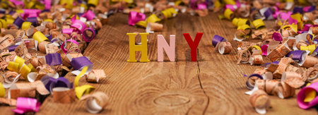 Happy New Year lettering, gift box with confetti on wooden background. Festive atmosphere. New year...