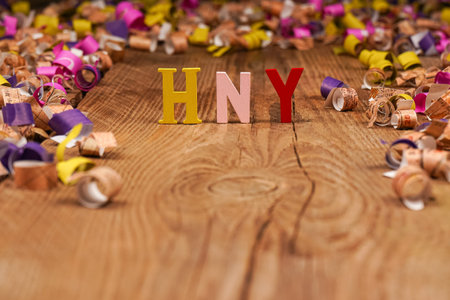 Happy New Year lettering, gift box with confetti on wooden background. Festive atmosphere. New year...