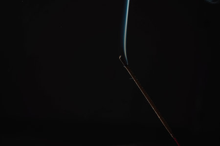 Incense burning smoke fumes and wisps. Burning aromatic incense smoky stick for meditation and relaxing. Aromatherapy smokes for yoga. Aroma sticks smoke on black background with white backlit.の写真素材