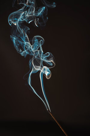 Aromatherapy smokes for yoga. Aroma sticks smoke on black background with white backlit. Burning aromatic incense smoky stick for meditation and relaxing. Incense burning smoke fumes and wisps.の写真素材