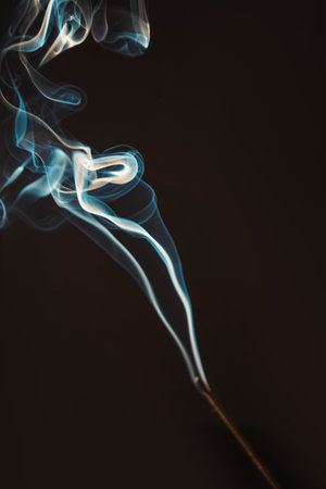 Aromatherapy smokes for yoga. Aroma sticks smoke on black background with white backlit. Burning aromatic incense smoky stick for meditation and relaxing. Incense burning smoke fumes and wisps.の写真素材