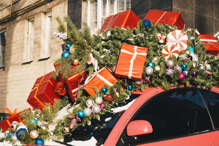 A classic Christmas automobile decorated with bells and garland and loaded with presents. A vintage car decorated for the holidays loaded with festive gifts. Christmas decorated classic car.の写真素材