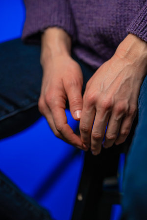 A female sitting on a chair in purple knitted sweater hands are down like she is giving up. Feeling powerless in some circumstances.の写真素材