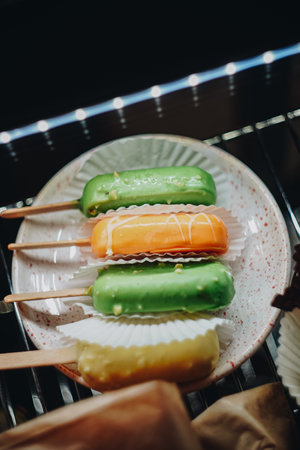 Cheesecakes on sticks of different colors at display case. Retail business of bakery and coffeeshops. Top view of deserts laying down in a plate.の写真素材