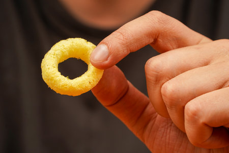 Eating onion rings. Onion ring. Deep fried onion rings. Snack for beer. Fast food. Junk food. Cooked tasty appetizer meal. Fried rings. Corn onion rings. Unhealthy food. Man holds onion ring.の写真素材