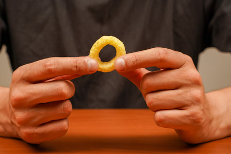 Junk food. Cooked tasty appetizer meal. Fried rings. Corn onion rings. Unhealthy food. Onion ring. Snack for beer. Fast food. Deep fried onion rings. Eating onion rings. Man holds onion ring.の写真素材