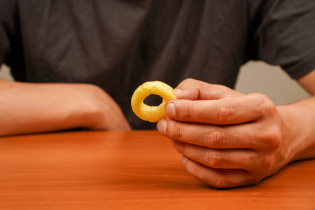 Onion ring. Deep fried onion rings. Snack for beer. Fast food. Junk food. Cooked tasty appetizer meal. Fried rings. Corn onion rings. Unhealthy food. Eating onion rings. Man holds onion ring.の写真素材