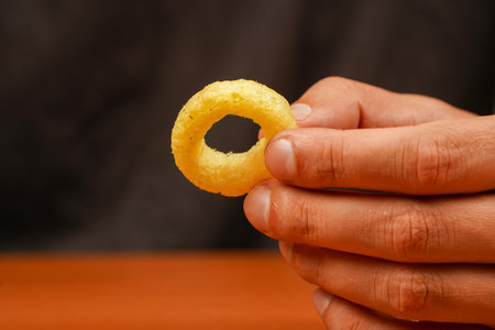 Snack for beer. Fast food. Junk food. Cooked tasty appetizer meal. Fried rings. Corn onion rings. Unhealthy food. Onion ring. Deep fried onion rings. Eating onion rings. Man holds onion ring.の写真素材