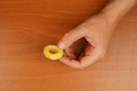 Cooked tasty appetizer meal. Fried rings. Corn onion rings. Unhealthy food. Onion ring. Snack for beer. Fast food. Deep fried onion rings. Eating onion rings. Man holds onion ring.の写真素材