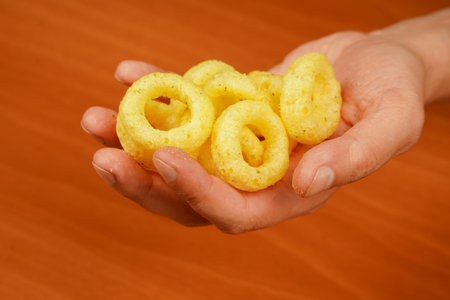 Man holds onion ring. Eating onion rings. Onion ring. Deep fried onion rings. Snack for beer. Fast food. Junk food. Cooked tasty appetizer meal. Fried rings. Corn onion rings. Unhealthy food.の写真素材