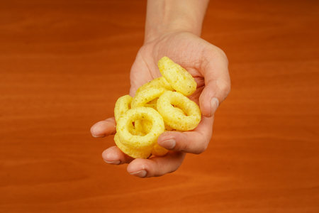 Fast food. Junk food. Cooked tasty appetizer meal. Fried rings. Corn onion rings. Unhealthy food. Man holds onion ring. Eating onion rings. Onion ring. Deep fried onion rings. Snack for beer.の写真素材