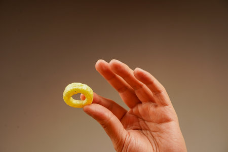 Onion ring. Deep fried onion rings. Snack for beer. Fast food. Junk food. Cooked tasty appetizer meal. Fried rings. Corn onion rings. Unhealthy food. Eating onion rings. Man holds onion ring.の写真素材