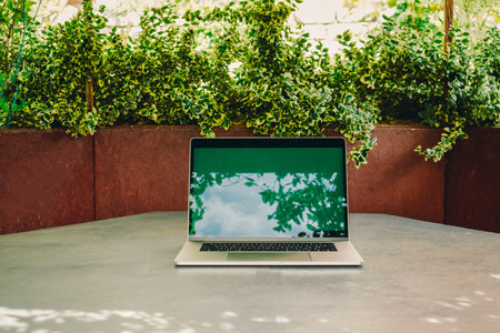 Open laptop with green screen on table. Working space outdoors with amazing view of nature. Modern laptop for work. Freelance from homeの写真素材