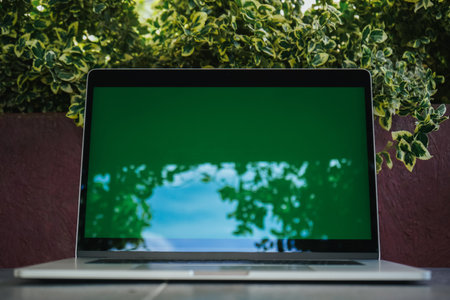 Open laptop with green screen on table background of nature. Working space outdoors with amazing view of nature. Modern laptop for work. Freelance from home.の写真素材