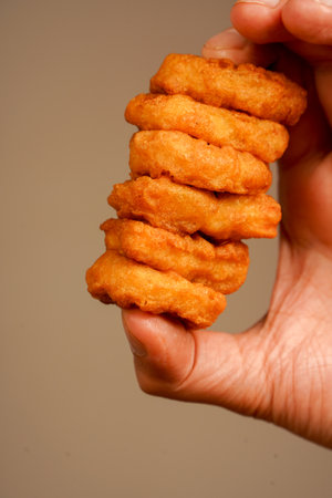 Unhealthy lifestyle. Fast food. Junk food. Chicken nuggets with ketchup. Holding chicken nuggets. Man eating chicken nuggets. Calories.の写真素材