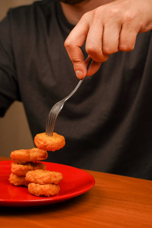 American food. Eating with fork. Man eating chicken nuggets. Chicken nuggets on fork. Fast food. Junk food. Unhealthy lifestyle. Calories. Obesity.の写真素材