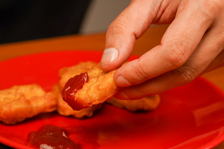 Man eating chicken nuggets. Chicken nuggets with ketchup. Holding chicken nuggets.の写真素材