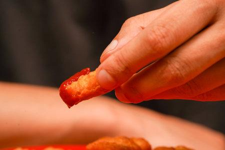 Chicken nuggets with ketchup. Holding chicken nuggets. Man eating chicken nuggets. Calories.の写真素材