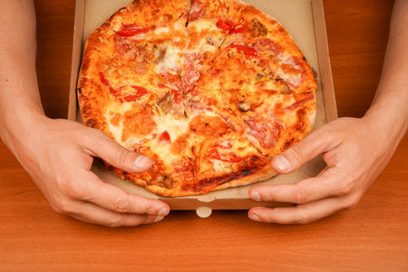 Tasty food at pizzeria. Concept of takeaway. Fast food order. Restaurant advertising. Delicious cheesy pizza. Pizza. Unhealthy food. Junk food. Fatty food. Hand taking pizza slice, close up view.の写真素材