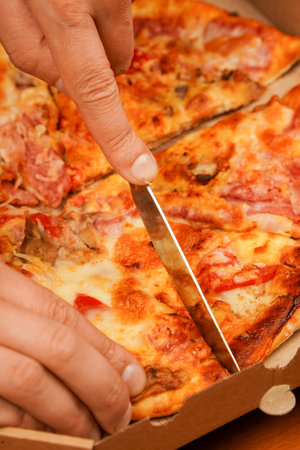 Fast food order. Restaurant advertising. Delicious cheesy pizza. Pizza. Unhealthy food. Junk food. Fatty food. Cutting pizza slice, close up view. Tasty food at pizzeria. Concept of takeaway.の写真素材