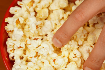 Flavored spicy popcorn. Bowl of tasty popcorn on wooden table. Delicious snack to eat in the cinema. Salted popcorn. Popcorn. Fast food. Junk food. Snack for cinema.の写真素材