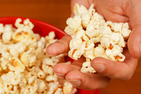 Delicious snack to eat in the cinema. Salted popcorn. Popcorn. Fast food. Junk food. Snack for cinema. Flavored spicy popcorn scattered on table surface. Bowl of tasty popcorn on wooden table.の写真素材