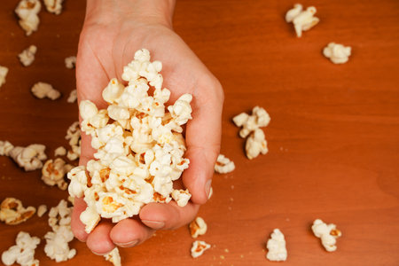 Delicious snack to eat in the cinema. Salted popcorn. Popcorn. Fast food. Junk food. Snack for cinema. Flavored spicy popcorn in mans hands.の写真素材