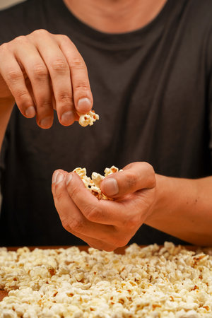 Man holding popcorn to eat. Delicious snack to eat in the cinema. Salted popcorn. Popcorn. Fast food. Junk food. Snack for cinema.の写真素材