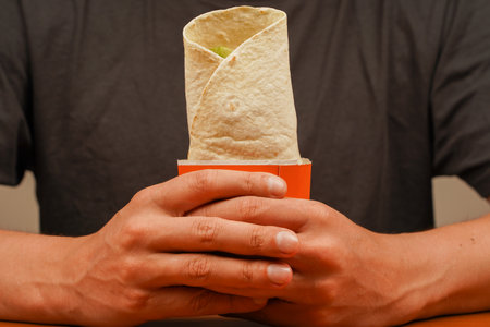 Fast food. Junk food. Eating. Food. Delicious. Chicken roll. Tortilla wrap with fried chicken meat and vegetables, close up. Shawarma tomato, cucumber, onion, lettuce and chicken meat.の写真素材