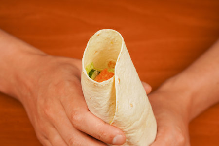 Tortilla wrap with fried chicken meat and vegetables, close up. Shawarma tomato, cucumber, onion, lettuce and chicken meat. Fast food. Junk food. Eating. Food. Delicious. Chicken roll.の写真素材
